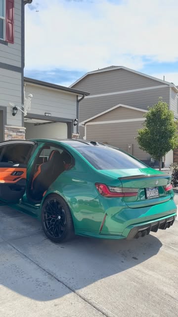 Green BMW in a driveway with its doors open